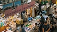 A bustling market with various stalls displaying seafood and other goods.