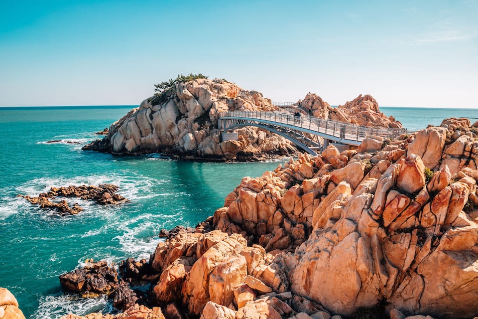 Une côte rocheuse avec un pont reliant deux portions de terre.