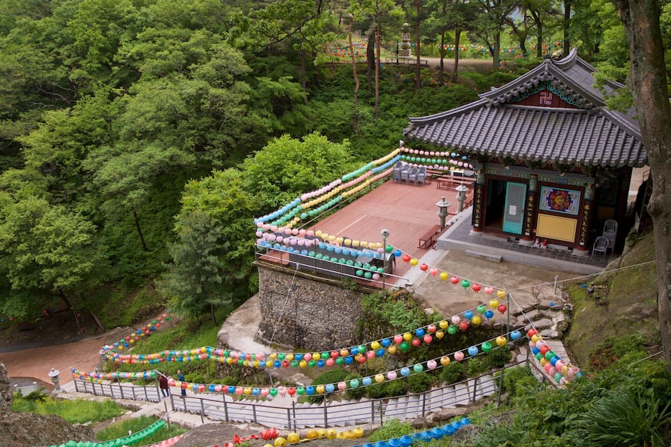 Un temple traditionnel, entouré d’une végétation luxuriante, avec des marches de pierre menant à son entrée.