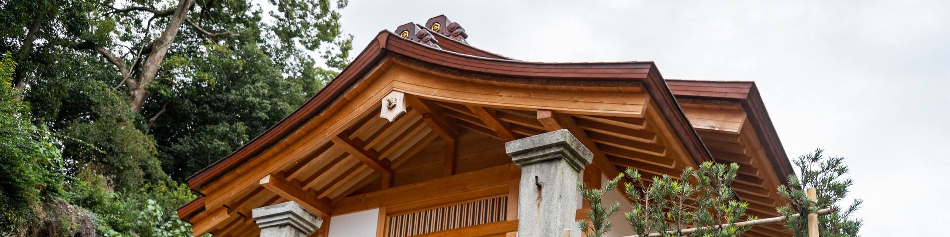 A traditional Japanese building with a wooden facade, stone pillars, and a stone lantern.