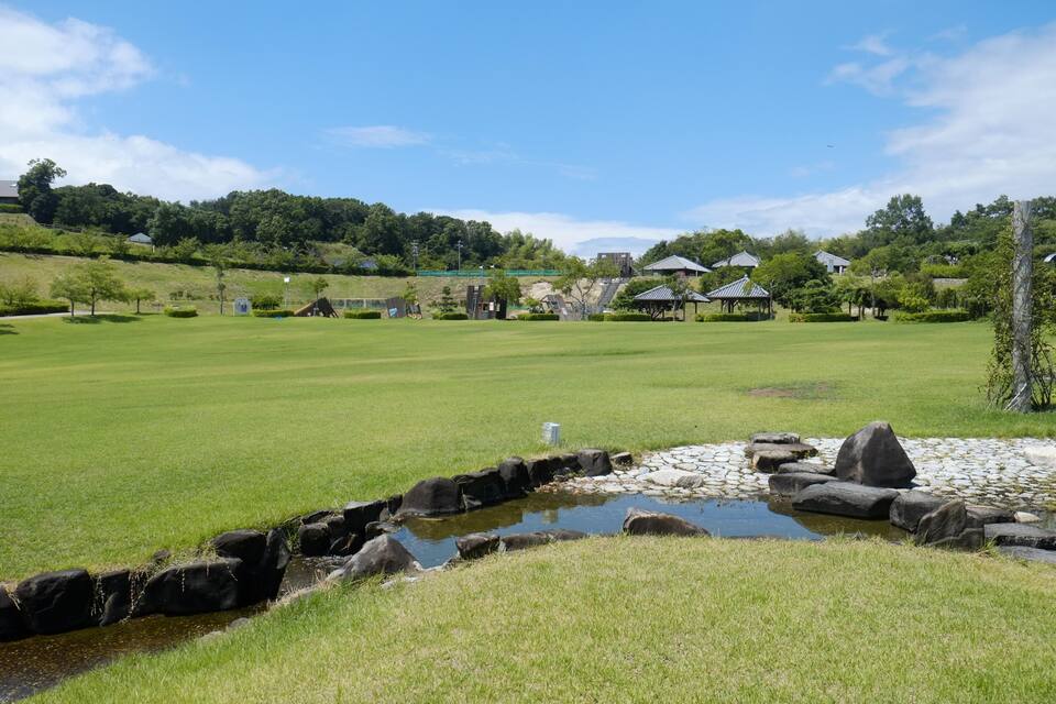 Un parcours de golf avec un étang, des rochers et des maisons en arrière-plan.