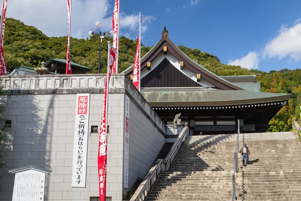 Um edifício japonês tradicional com telhado inclinado e escadaria de pedra que leva até ele.