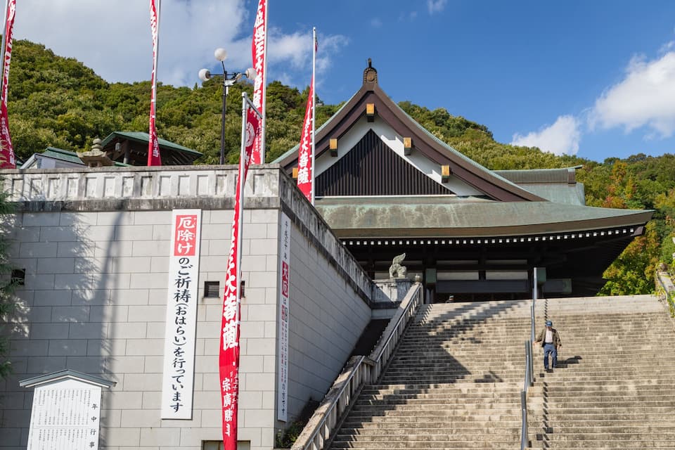 Ein traditionelles japanisches Gebäude mit einem geneigten Dach und einer Steintreppe, die zu ihm hinaufführt.