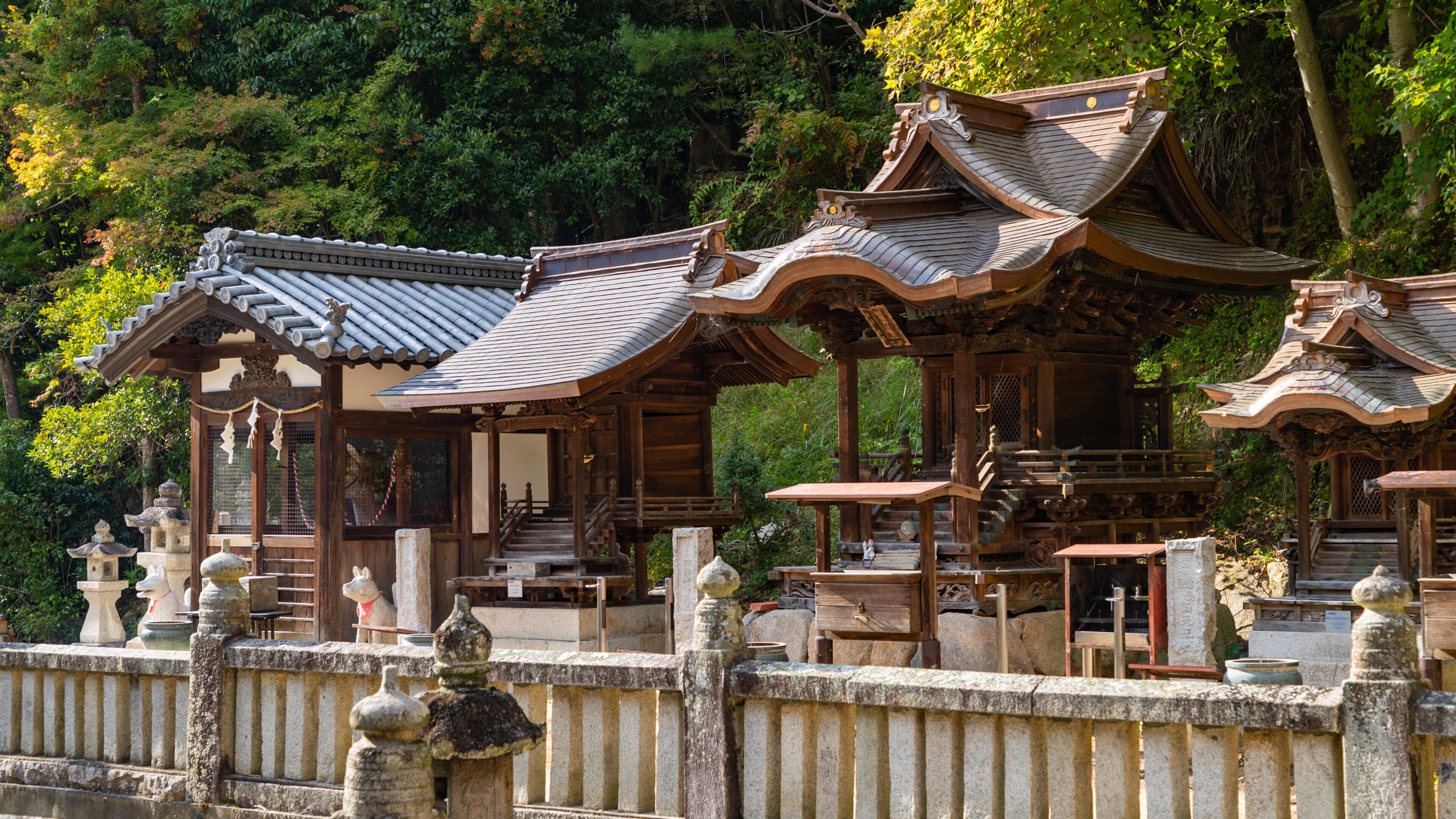 Traditional wooden structures with curved roofs, surrounded by stone railings and lush greenery.
