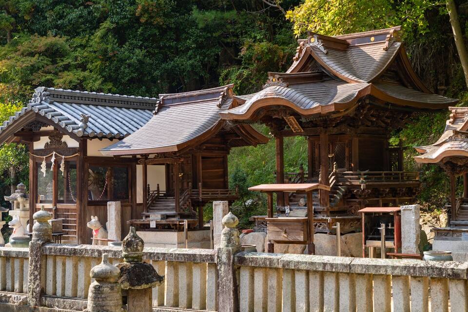 Traditional wooden structures with curved roofs, surrounded by stone railings and lush greenery.