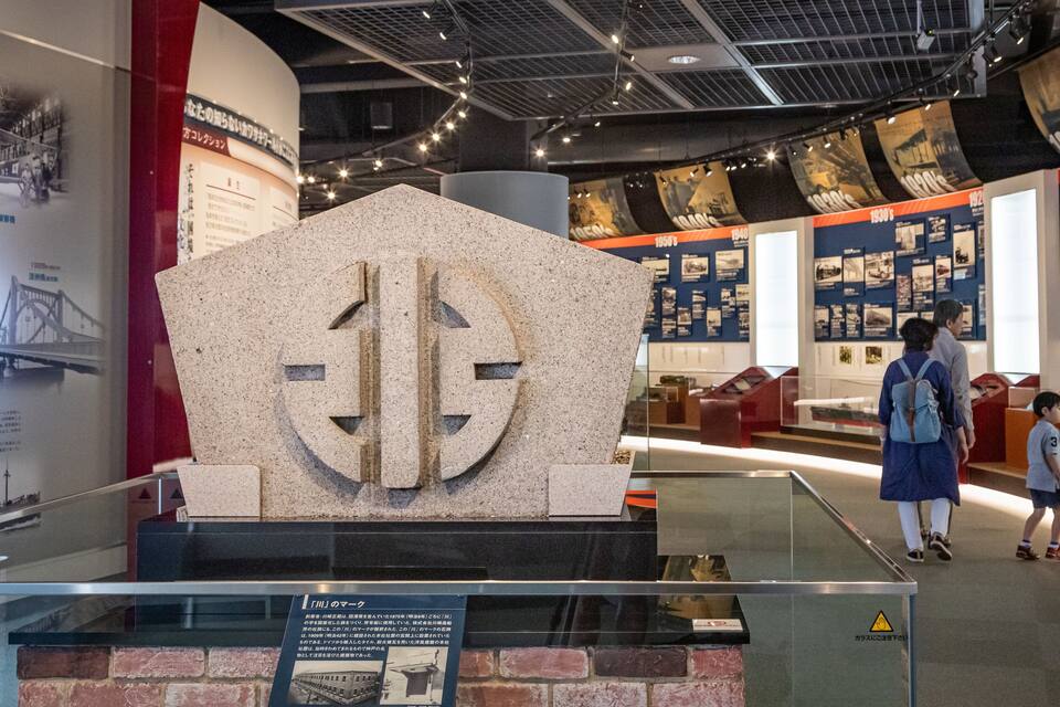 A museum interior with a large stone sculpture, informational displays, and a child walking.