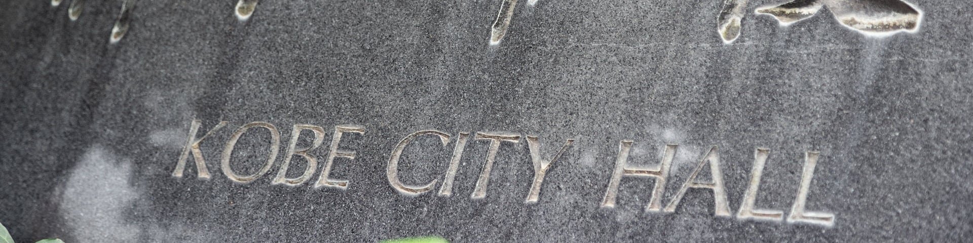 A stone plaque with Japanese characters and the English text "KOBE CITY HALL".
