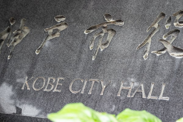 Une plaque de pierre portant des caractères japonais et le texte en anglais : « KOBE CITY HALL ».