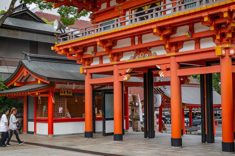 Een traditionele Japanse poort met rode pilaren en een zwart dak.