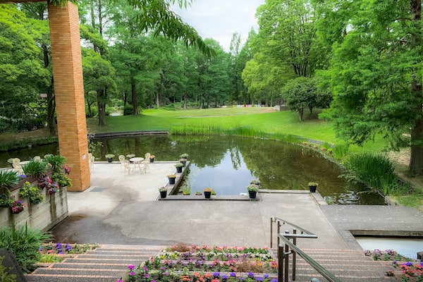 A serene park with a pond, a wooden pavilion, and a well-maintained lawn.