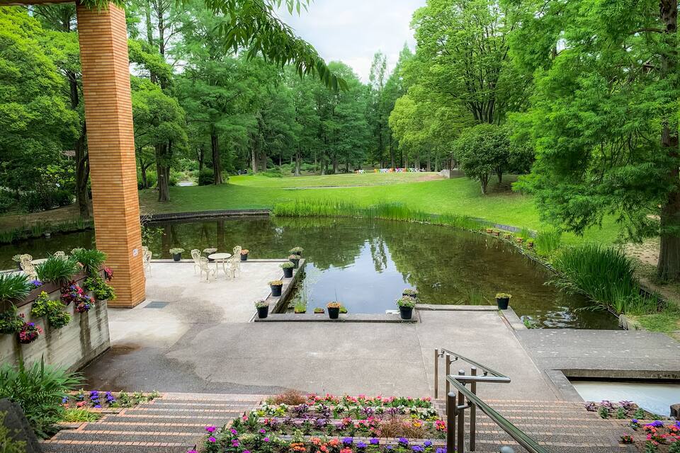 A serene park with a pond, a wooden pavilion, and a well-maintained lawn.