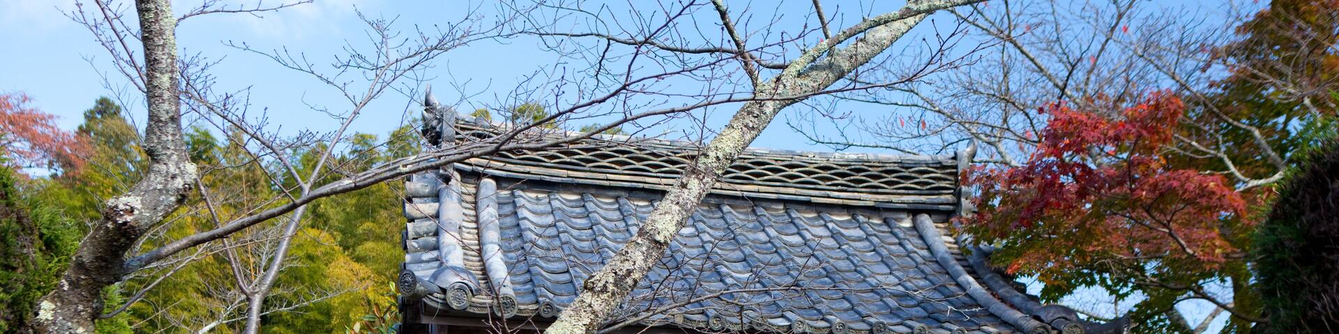A traditional Japanese building with a tiled roof, wooden pillars, and a signboard.