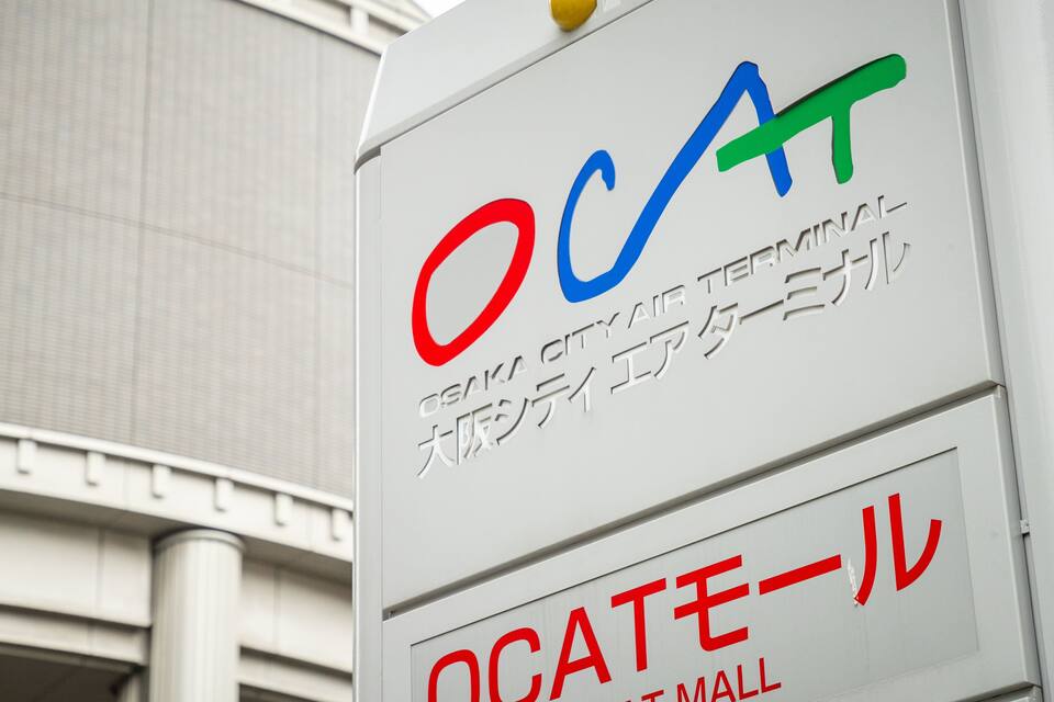 Un letrero con las letras "OCA" y la inscripción "OSAKA CITY AIR TERMINAL" tanto en inglés como en japonés.