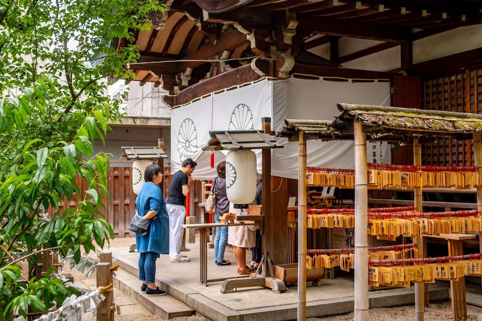 A traditional Japanese shrine with wooden structures, a pagoda, and visitors.