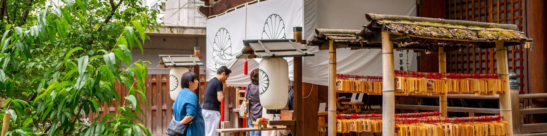 Um santuário japonês tradicional com construções de madeira, uma pagoda e visitantes.