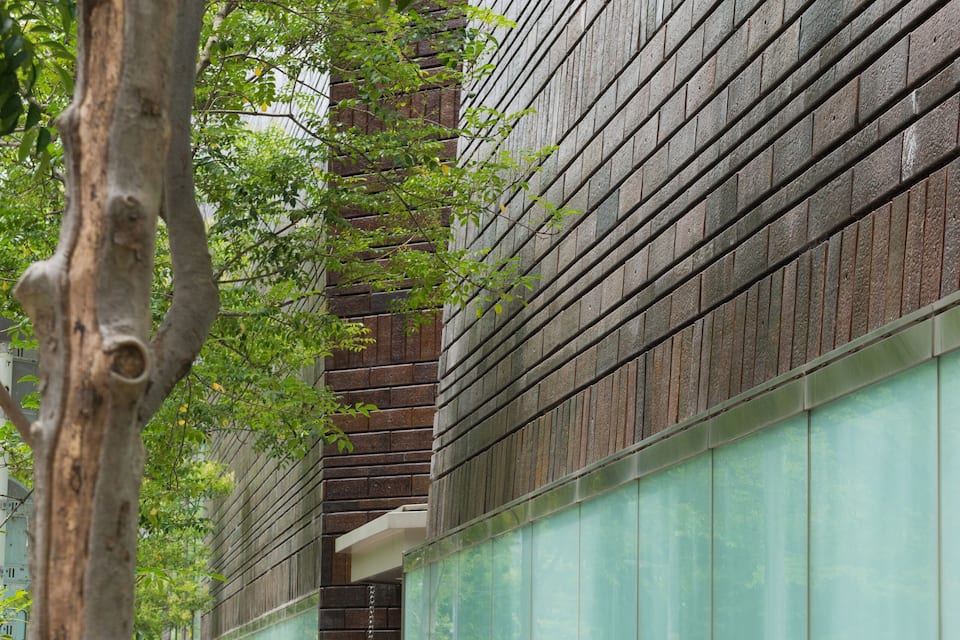 A modern building with a glass facade and a tree-lined sidewalk.