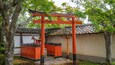 A traditional Japanese torii gate in a serene garden with a temple in the background.