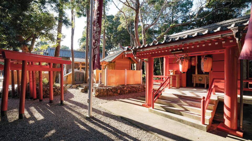 A traditional Japanese shrine with red torii gates, stone lanterns, and a wooden building with a tiled roof.
