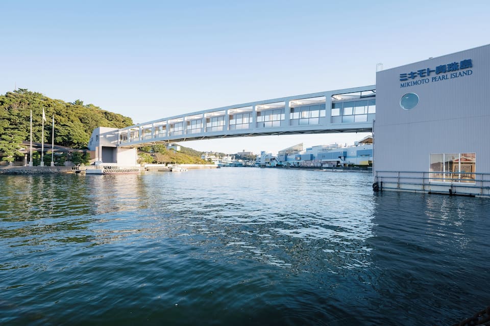 A modern bridge over water with a building labeled "Mikimoto Pearl Island" on the right.