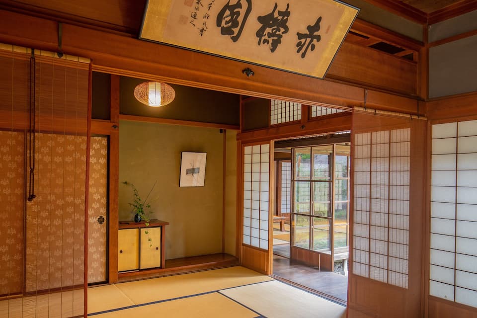 Um quarto japonês tradicional com tatames, portas corrediças e um lanterna pendurada.