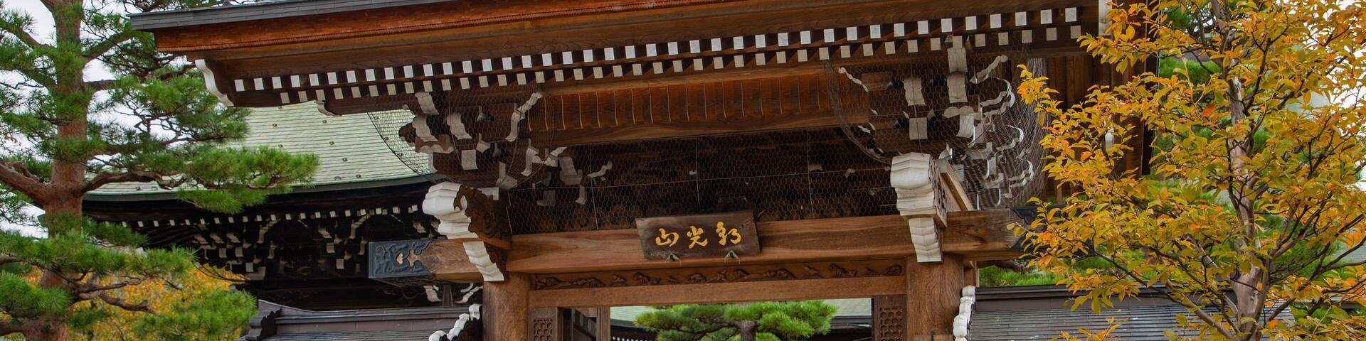 A traditional Japanese gate with intricate wooden carvings and a signboard.