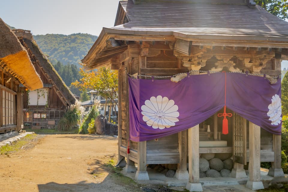 A traditional wooden structure with a thatched roof and a purple decorative cloth.