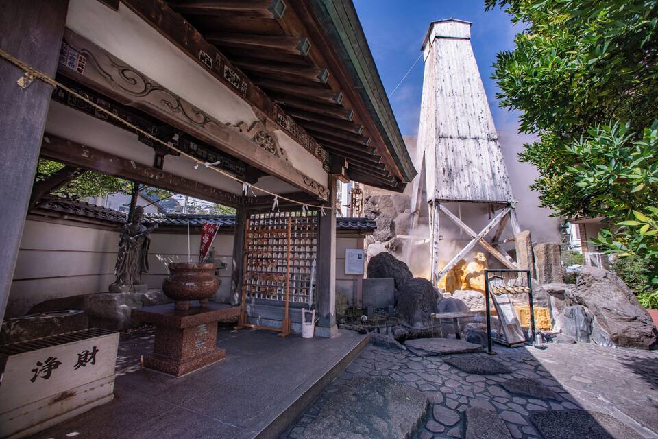 Un santuario japonés tradicional con un farol de piedra, vigas de madera y un muro de piedra.