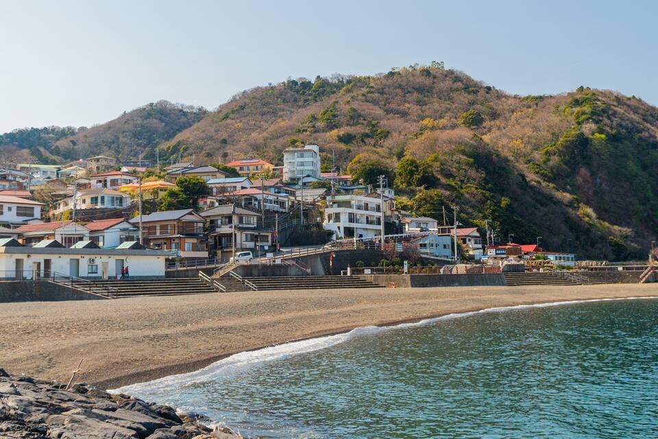 A coastal town with buildings on a hillside overlooking the beach.