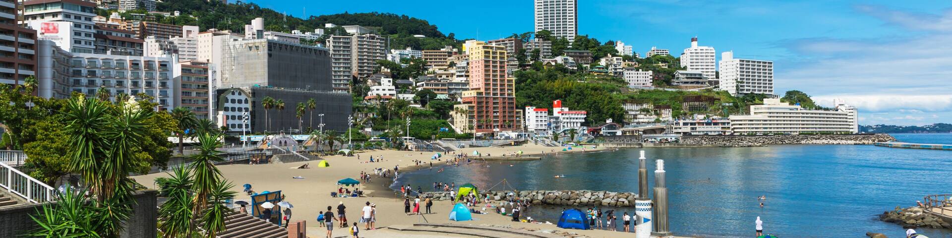 A coastal cityscape with a beach, palm trees, and a prominent tall building.