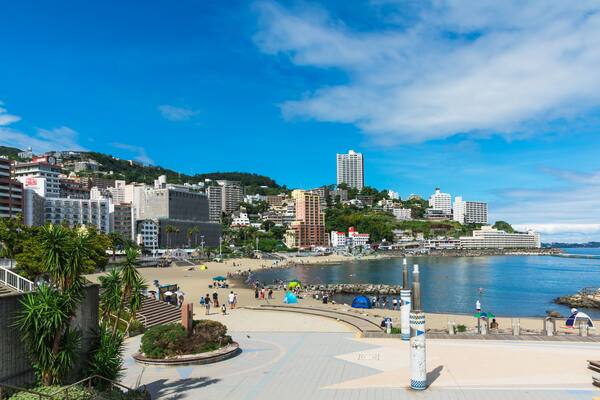 Un paysage urbain côtier avec une plage, des palmiers et un grand bâtiment imposant.