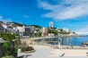 A coastal cityscape with a beach, palm trees, and a prominent tall building.