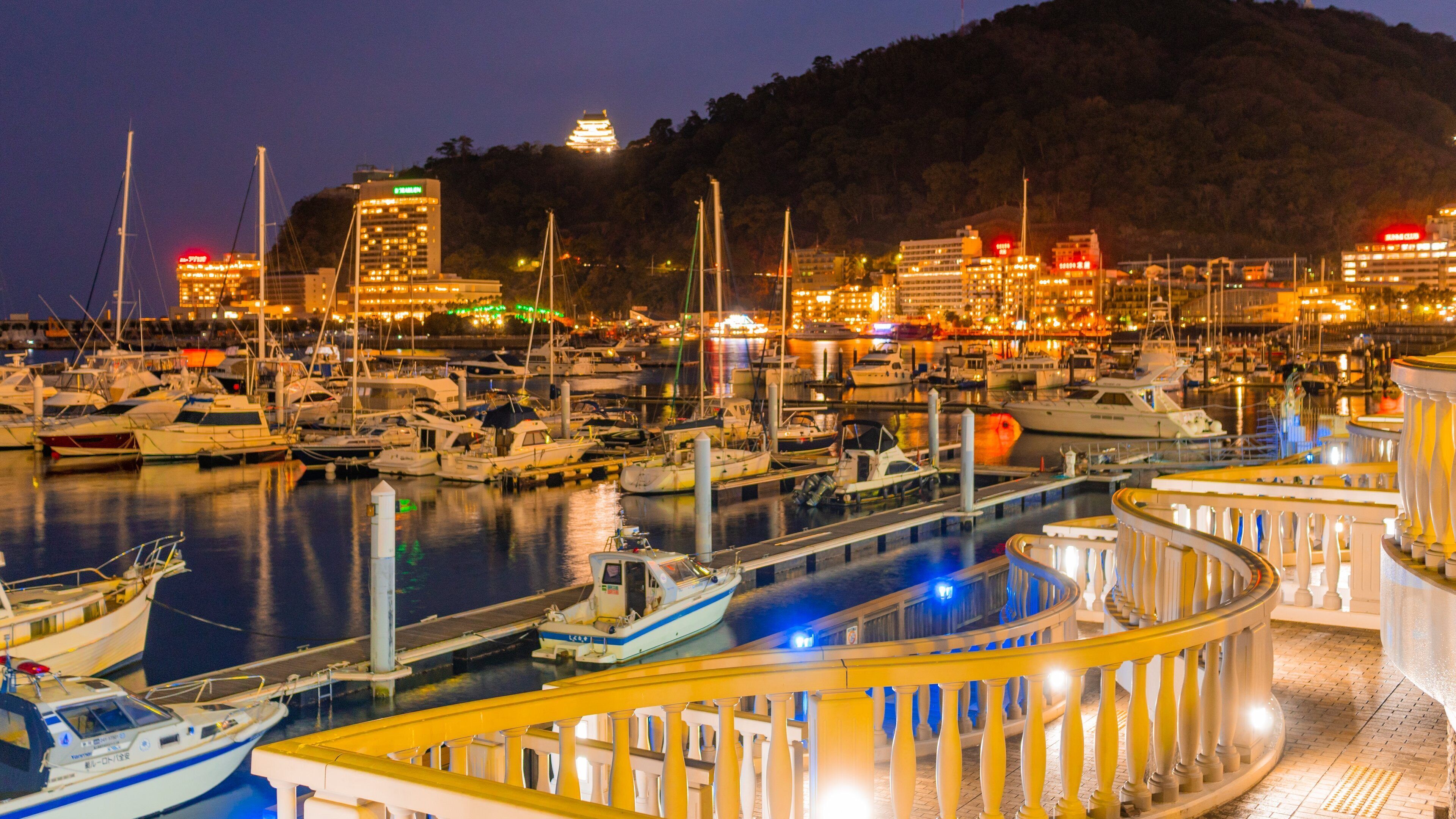 A marina at dusk with boats docked and a traditional building in the background.