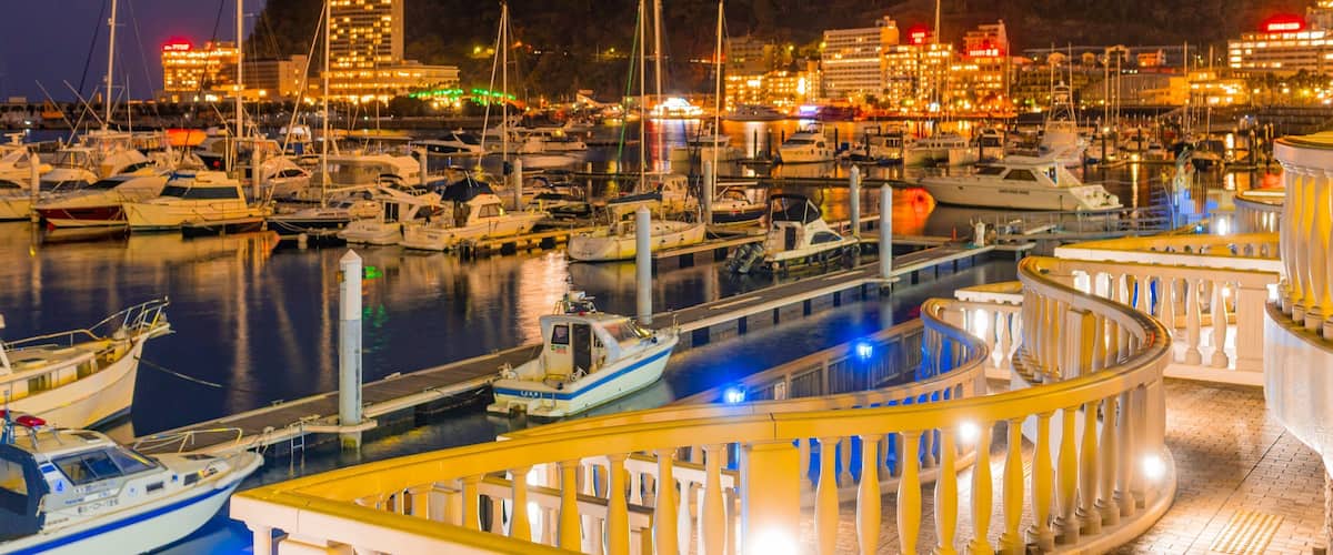 A marina at dusk with boats docked and a traditional building in the background.