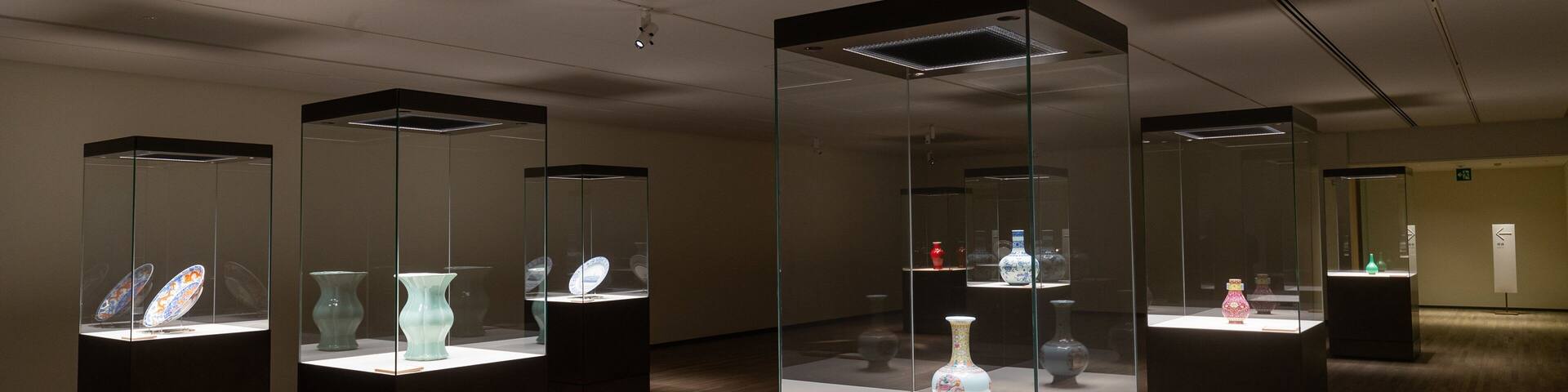 A museum interior with glass display cases containing ceramic vases.