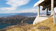 Une tour d’observation en béton offrant une vue panoramique sur un paysage montagneux, avec un lac et des vues sur la ville au loin.
