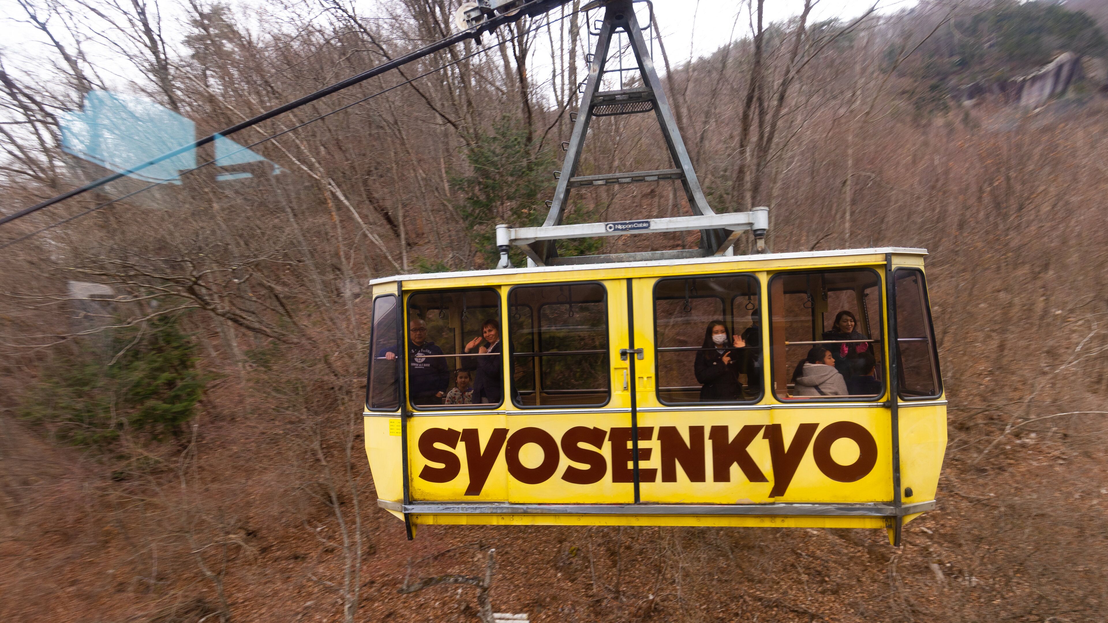 Shosenkyo Ropeway showing signage and a gondola as well as a small group of people