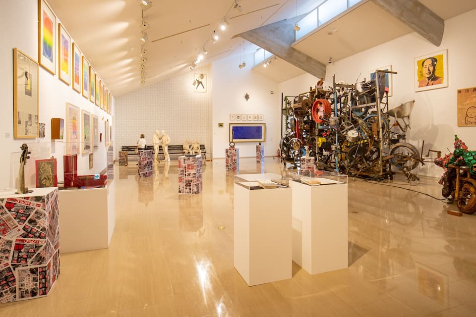An art gallery with various artworks, including sculptures and paintings, displayed on walls and pedestals.