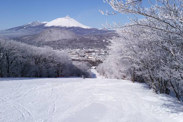 Schneebedeckte Landschaft mit einem Berg im Hintergrund und einer Stadt in der Ferne.
