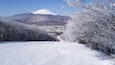 A snowy landscape with a mountain in the background and a town in the distance.