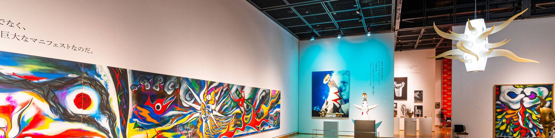 An art gallery with large colorful paintings on the walls and a wooden floor.