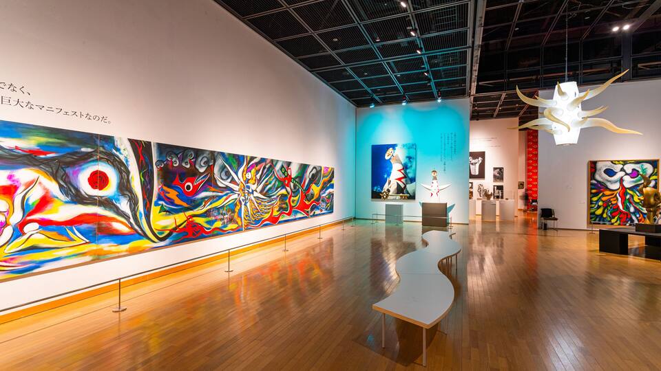An art gallery with large colorful paintings on the walls and a wooden floor.