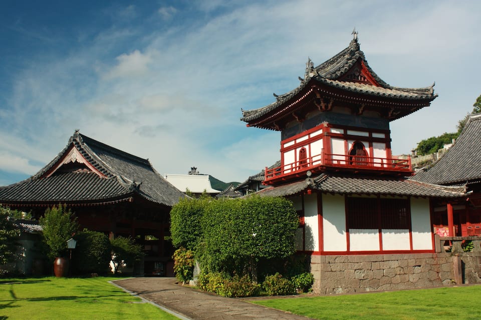 A traditional Korean temple with a prominent red and white structure, surrounded by lush greenery and traditional architecture.
