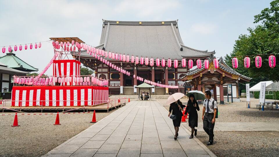 A traditional Japanese temple with a large gate and pink lanterns.