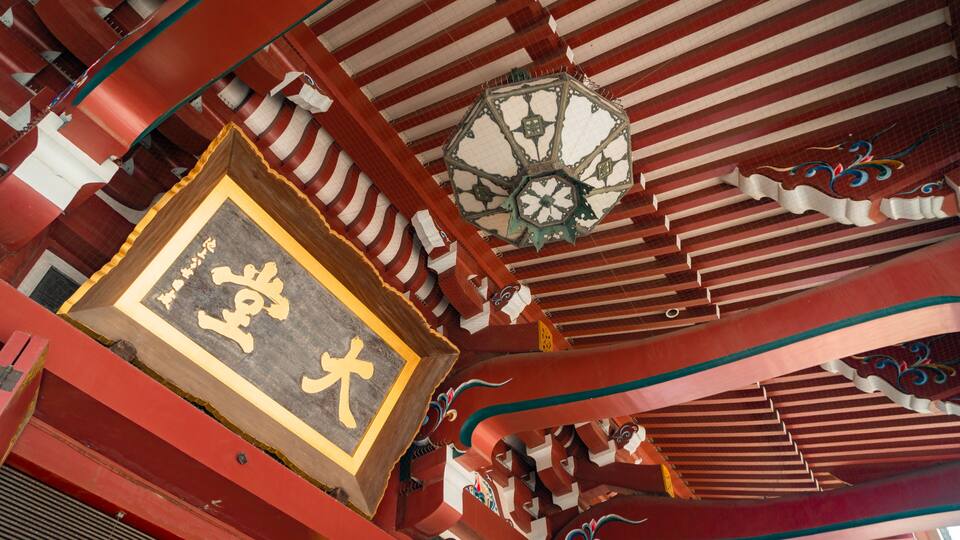 A traditional Chinese architectural structure with ornate red and white decorations, a large ornate clock, and a framed sign with Chinese characters.