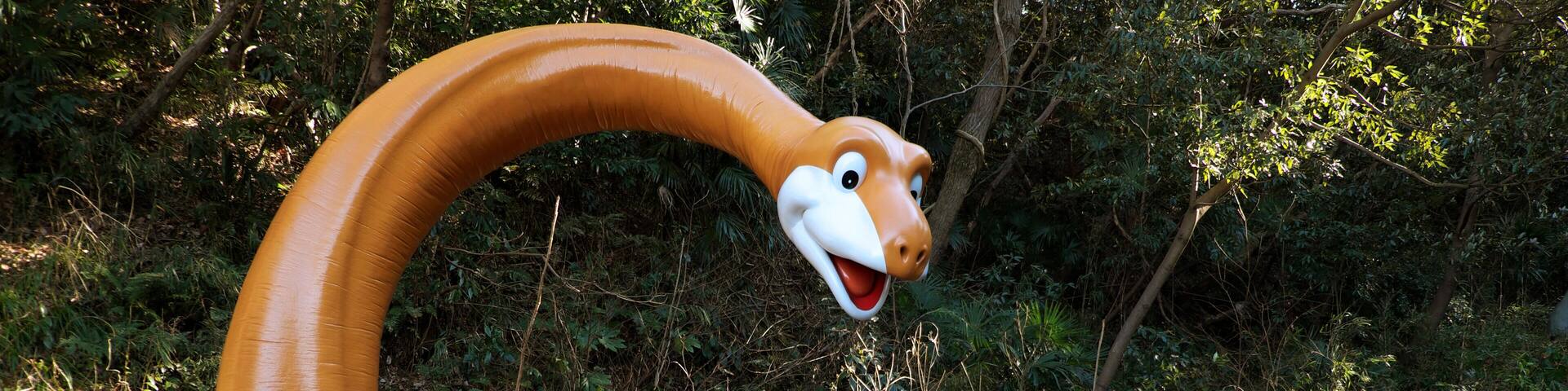 A large dinosaur sculpture with a smiling face and a character sitting on its back.