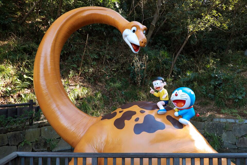 A large dinosaur sculpture with a smiling face and a character sitting on its back.