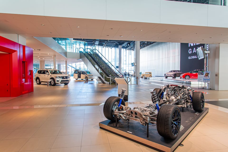 A modern car showroom with various vehicles on display, including a prominently featured car engine model.