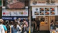 A busy street with a food stall advertising grilled wagyu beef and another with takarabune.