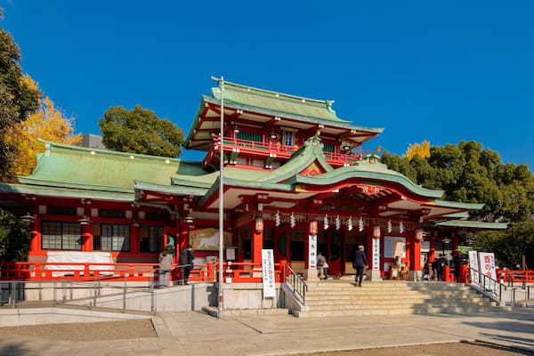 Um templo japonês tradicional com telhado de vários níveis e detalhes em vermelho e verde.
