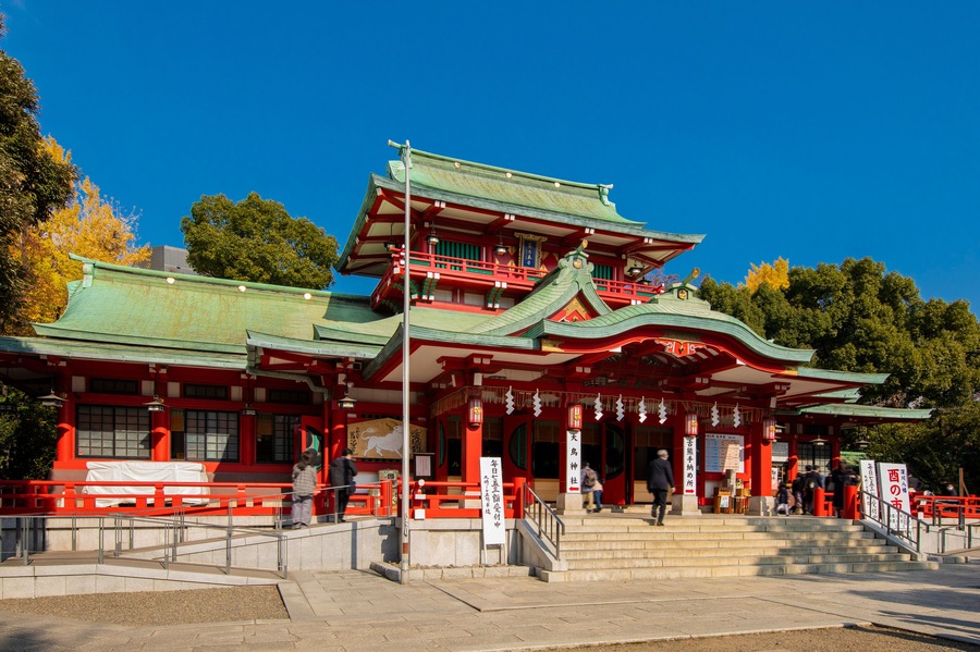 A traditional Japanese temple with a multi-tiered roof and red and green accents.